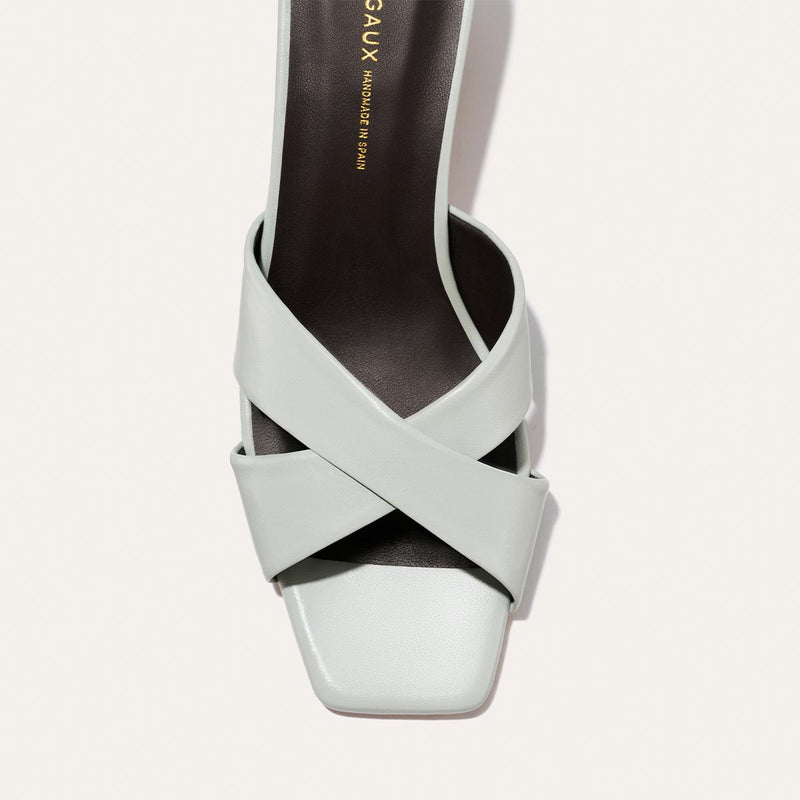 Light blue sandal with criss-cross straps on a light gray background