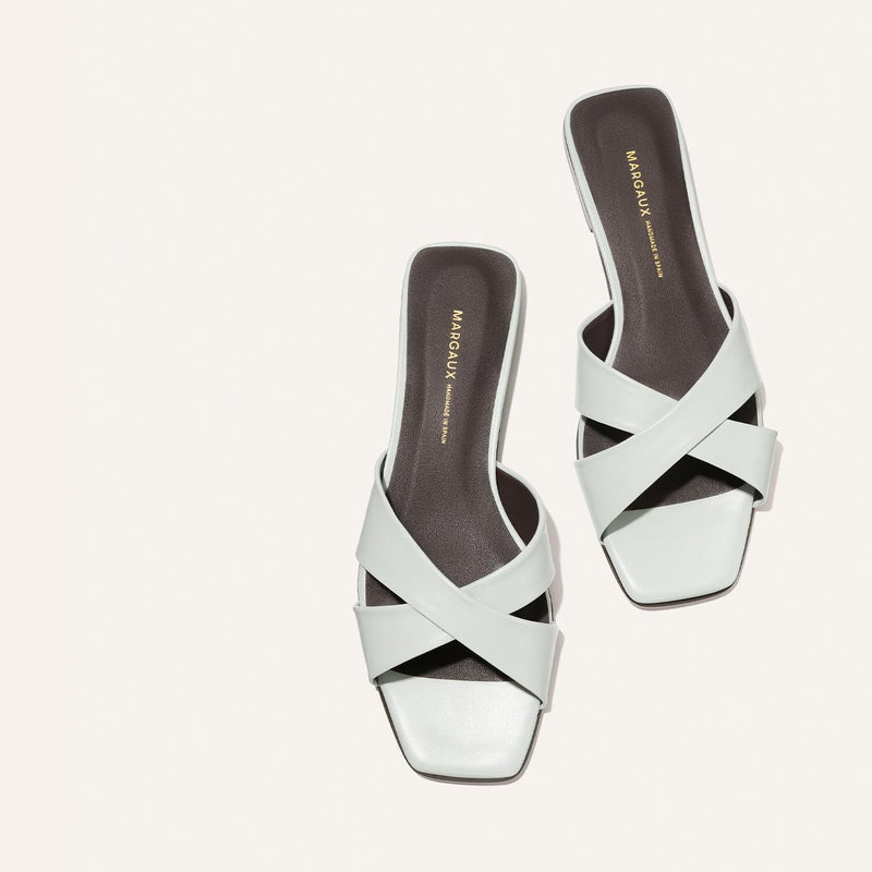 Light blue sandals with criss-cross straps on a white background