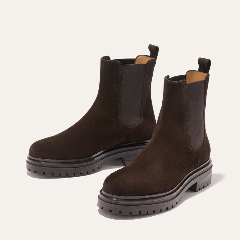 The West Chelsea Boot - Cocoa Suede by margaux-development: dark brown water-resistant suede boots with thick rubber lug soles, elastic side panels, and back pull tabs, shown on a light background.