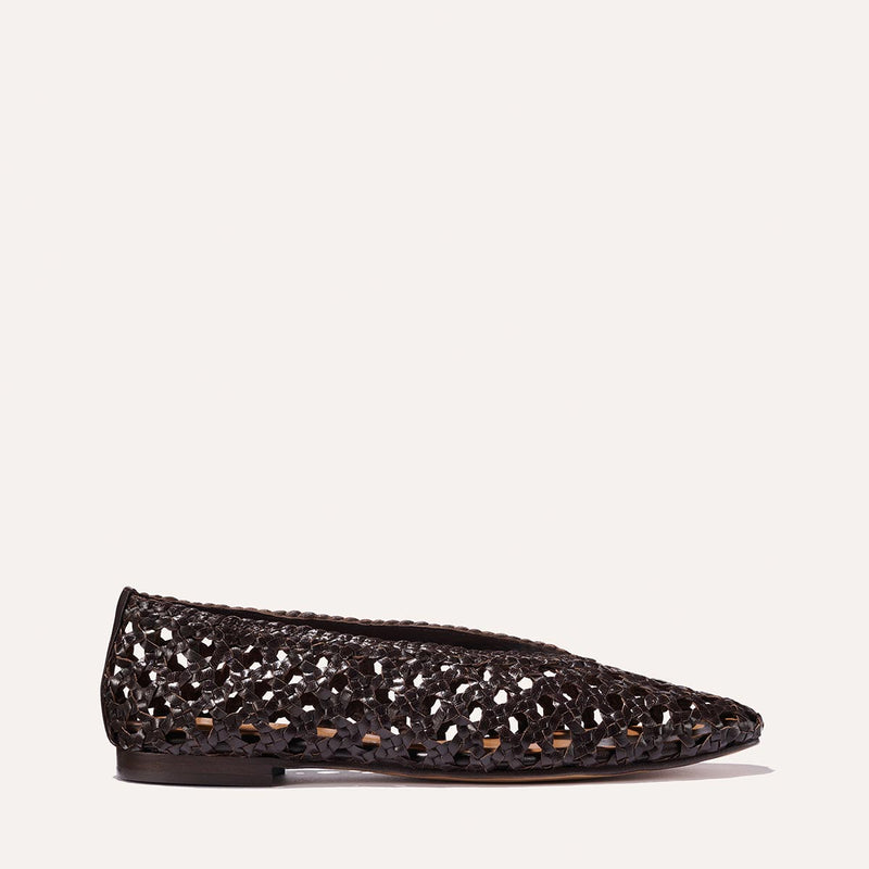 The Woven Paz SS25 flat shoe by Margaux, shown in profile against a plain light background, features handwoven espresso leather, a pointed toe, and a cut-out design.
