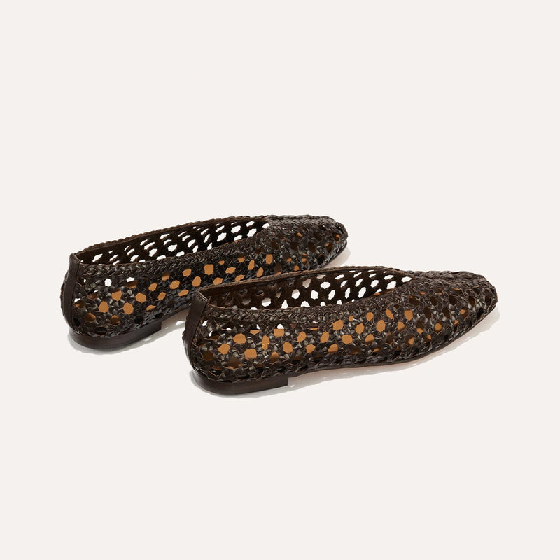 A pair of Margaux’s The Woven Paz SS25 flats in Espresso Leather, handwoven with a cut-out lattice design, are shown on a light background with one shoe slightly overlapping the other.
