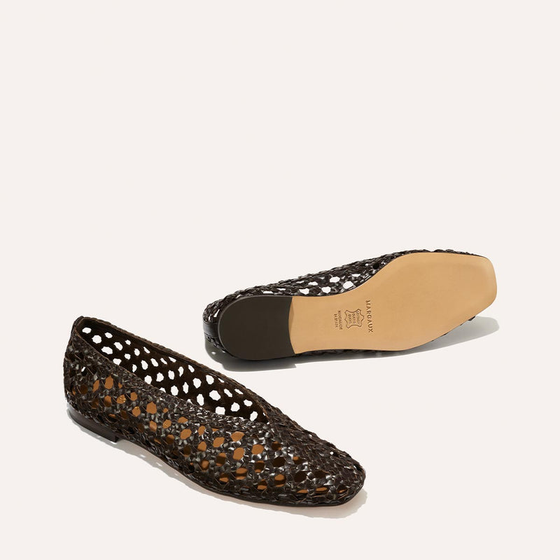 A pair of Margaux’s The Woven Paz SS25 flats in Espresso Leather—one upright, the other showing its tan sole—are displayed against a plain light background.