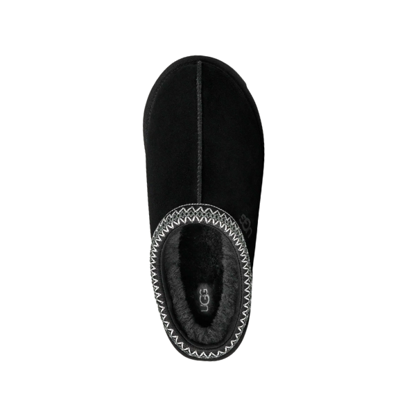 The UGG Men's Tasman II Black slipper features a black suede upper, sheepskin-lined interior, decorative stitching, and an UGG logo on the insole. The photo shows a top-down view against a white background.