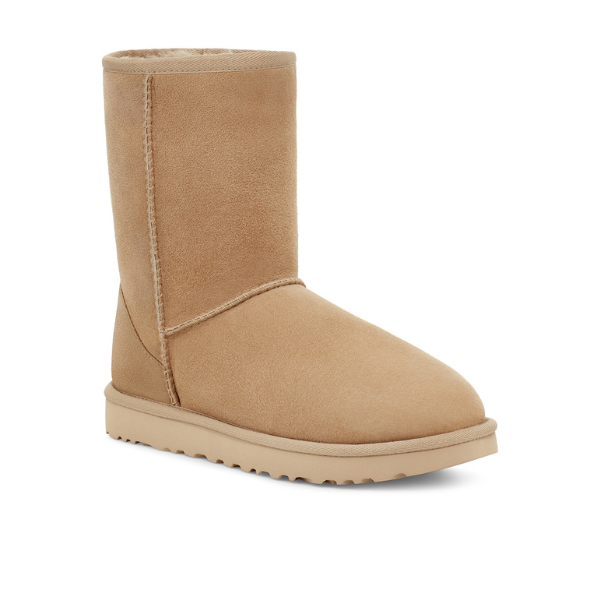 The UGG Womens Classic Short II Boot in Mustard Seed is a tan, mid-calf sheepskin winter boot with a flat sole and visible stitching—designed for warmth and foot comfort, shown against a white background.