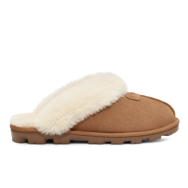 A side view of the UGG Womens Coquette Slipper Chestnut shows plush white faux fur lining, tan suede upper, and a textured rubber sole.
