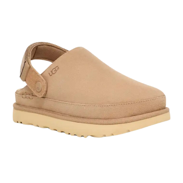 The UGG Womens Goldenstar Clog Sand features a tan closed toe, open heel, adjustable strap, and a thick textured rubber sole, combining trendy platform clog style with signature UGG comfort.