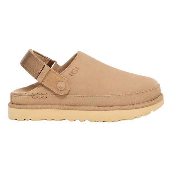 The UGG Womens Goldenstar Clog Sand features a tan suede upper, closed toe, adjustable heel strap, and textured rubber sole with an embossed UGG logo near the strap for classic comfort and style.