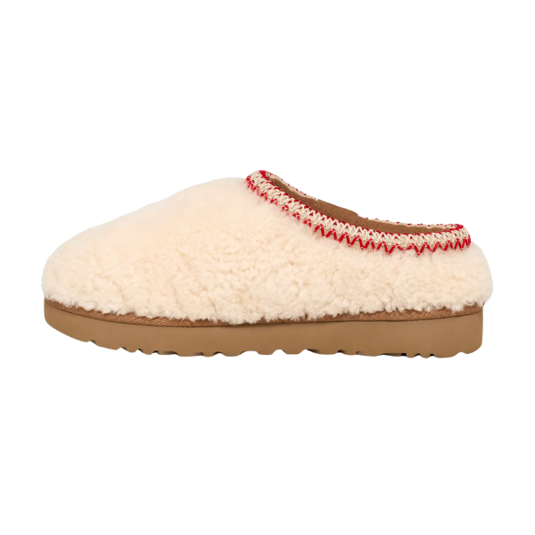 The UGG Women's Tasman Maxi Natural slipper features a fuzzy cream sheepskin upper, tan sole, slip-on design, and an opening trimmed with red and white stitching, echoing the cozy style of UGG’s classic collections.