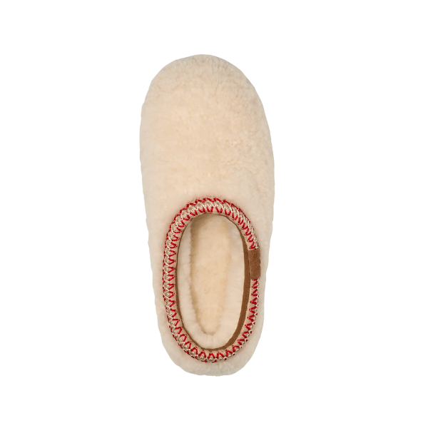 A single UGG Women's Tasman Maxi Natural slipper in cream sheepskin, shown from above with a rounded toe and red-and-white stitched trim around the opening. The plain background highlights its design. Brand: UGG.