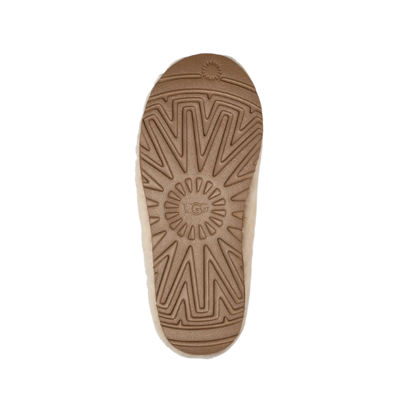 The image features the sole of the UGG Women's Tasman Maxi Natural boot in tan, displaying a textured zigzag and sunburst pattern with the UGG logo embossed in the center. The background is white.